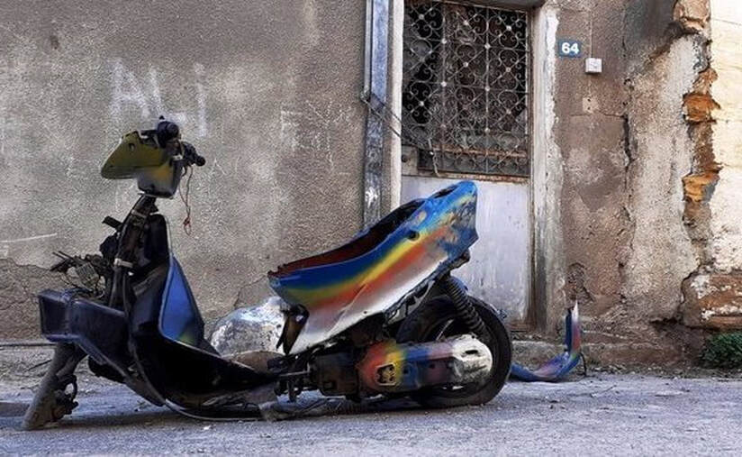 Abandoned rainbow painted motorcycle scooter in the streets