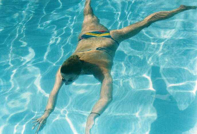 A snap of a female swimming underwater in a pool with the water distortion creating an effect