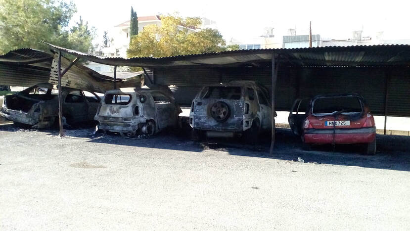 A row of burnt out cars in a lot. Arson